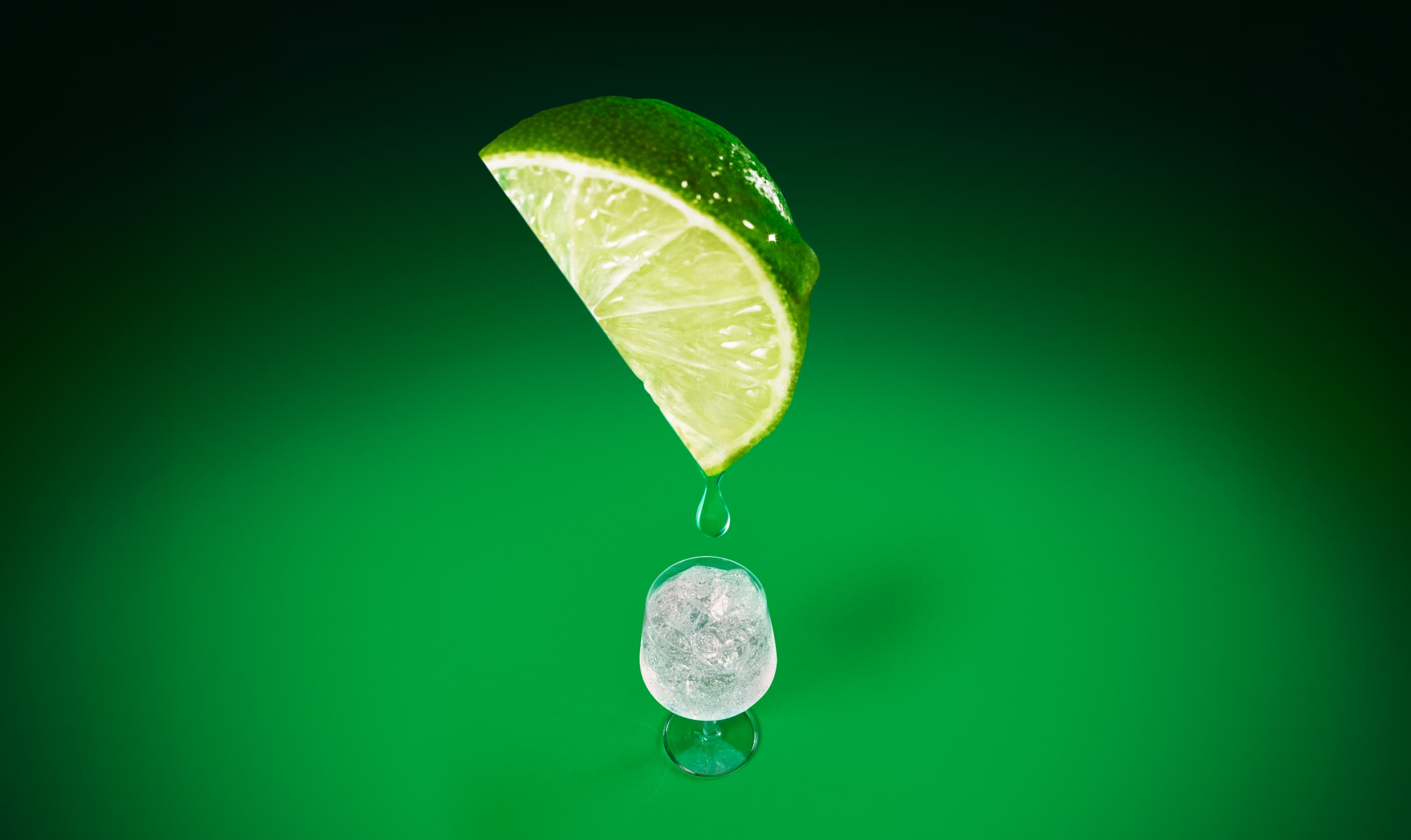 A rocks glass of crystal-clear liquid with ice and a hand reaching for the glass.