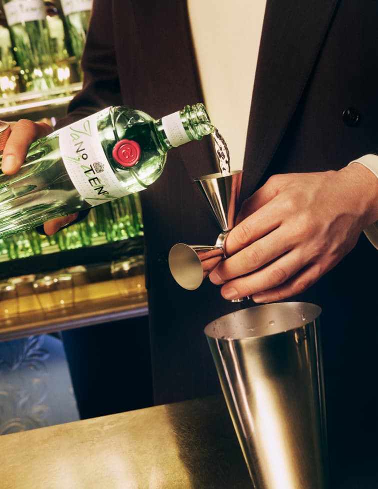 A hand pouring Tanqueray No. Ten into a jigger. 