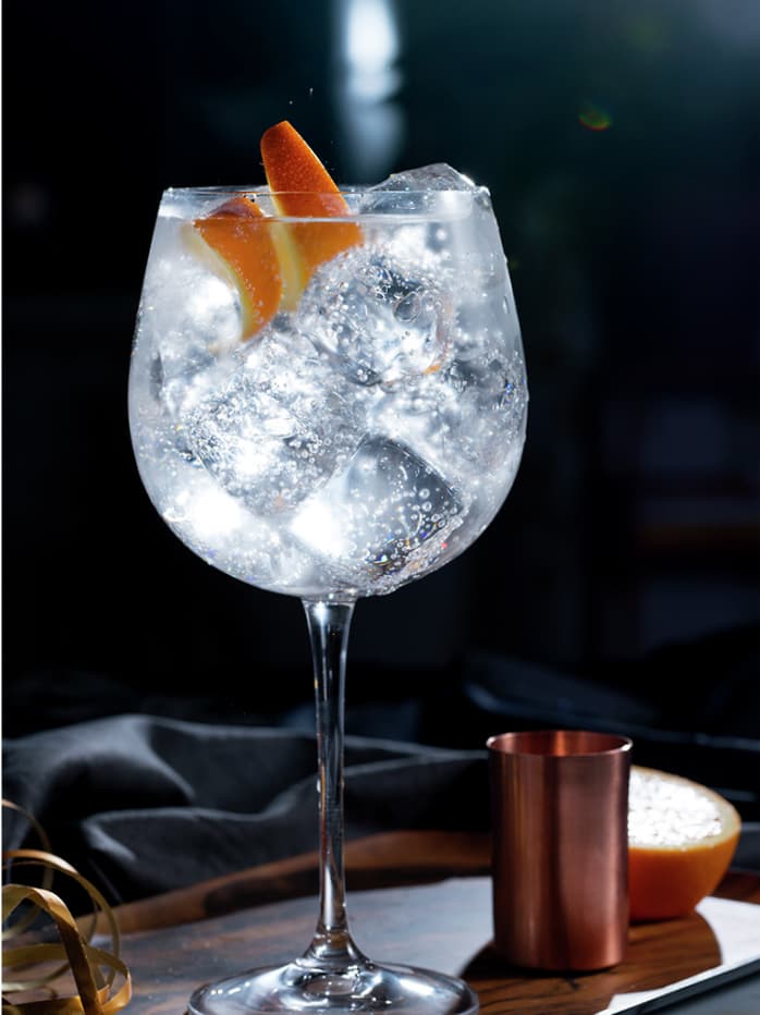 A Gin & Tonic made with Tanqueray London Dry Gin and garnished with an orange peel
